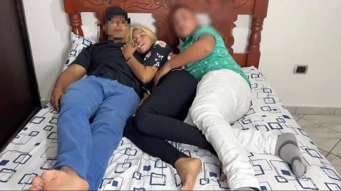 Os caras e a loira estão deitados e transando em uma cama grande.