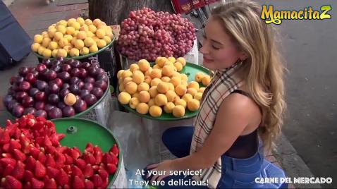 Uma loira compra frutas na rua.